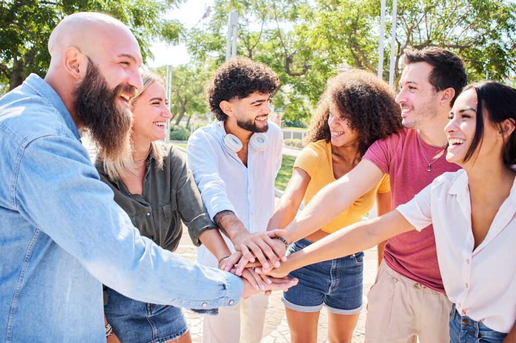 Group of people having fun together. Multiracial smiling friends stacking hands in a happy circle.